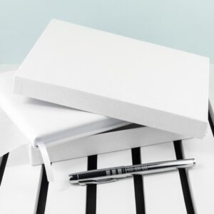 Wit lederen gastenboek liggend in een geopende witte luxe geschenkdoos met een bijpassende zilveren pen.