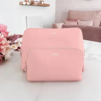Stijlvolle roze make-up tas in kunstleer met witte bedrukking van initialen, voorzien van gouden ritssluiting en ideaal als cadeau