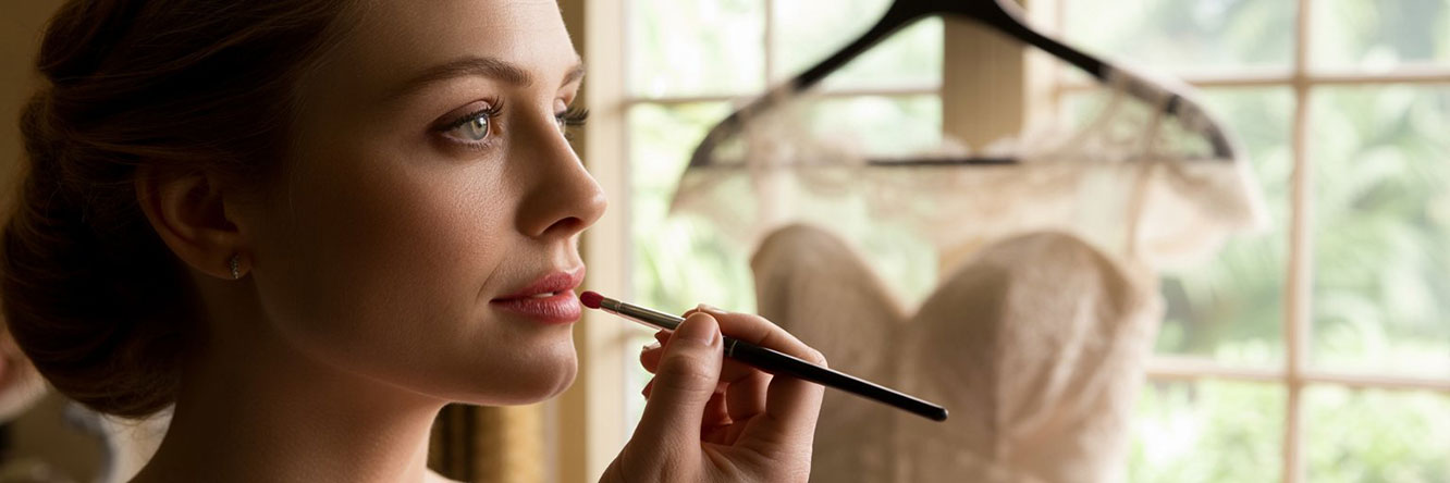 Intieme close-up van een visagist die de make-up van een serene bruid aanbrengt, een belangrijk onderdeel van de voorbereiding op de grote dag.
