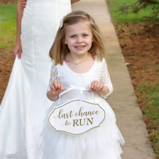 Bruidsmeisje met wit 'last chance to run' bordje voor de ceremonie entree