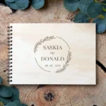 Houten gastenboek met gegraveerde eucalyptus krans en namen in Perfect Serif lettertype