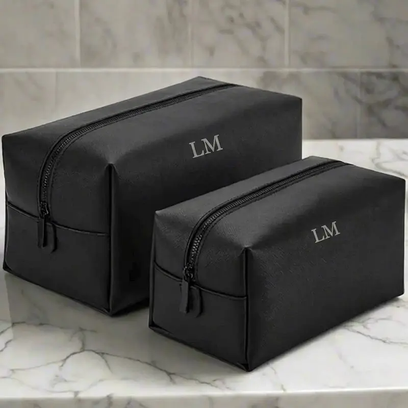Gepersonaliseerde-toilettas-met-initialen--Zwart-leer-look Zwarte toilettas met gegraveerde initialen LM, groot en klein formaat op marmeren ondergrond