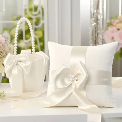 Ivoorkleurige bruiloft set, bestaande uit een satijnen ringkussen en een bijpassend bloemenmandje, beide versierd met parels en een strik