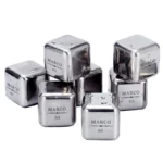 Acht gepolijste RVS whiskey stenen met individuele gravure van naam en leeftijd, inclusief stalen tang en vries-tray.