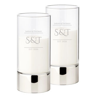 Set van twee zilverkleurige windlichten met wit-matte glasgravure 'S&T EST. 2026' in een modern minimalistisch design.