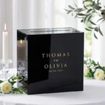 Zwarte acryl enveloppendoos met goud spiegel branding op een gedekte cadeautafel.