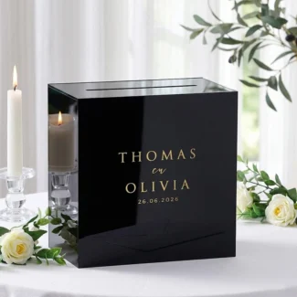 Zwarte acryl enveloppendoos met goud spiegel branding op een gedekte cadeautafel.
