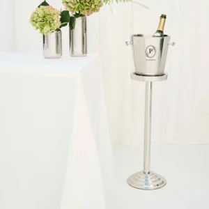 Luxe RVS wijnkoeler op hoge standaard in een stijlvol interieur met bloemen en witte tafel.