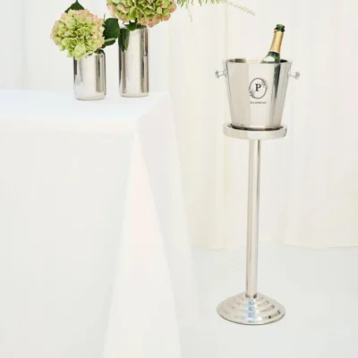 Luxe RVS wijnkoeler op hoge standaard in een stijlvol interieur met bloemen en witte tafel.