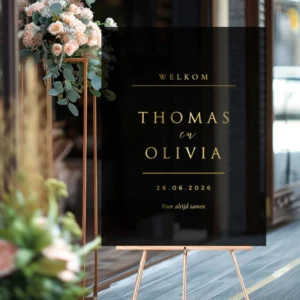 Rechthoekig zwart acryl welkomstbord op een goudkleurige ezel met spiegelende gouden gravering van namen en trouwdatum.