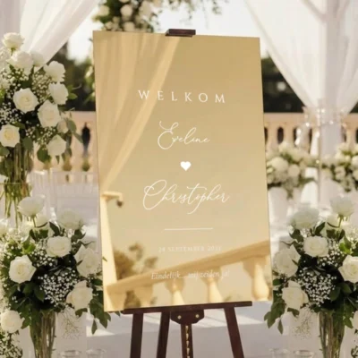Gold mirror welkomstbord Love Heart op houten ezel bij buitenlocatie met witte bloemen en gordijnen