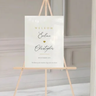 Gepersonaliseerd welkomstbord Love Heart Edition op wit acryl met sierlijk kalligrafie-schrift en gouden hartje op houten ezel