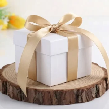 Wit cadeauboxje gestrikt met luxe champagne satijn lint op een houten ondergrond.