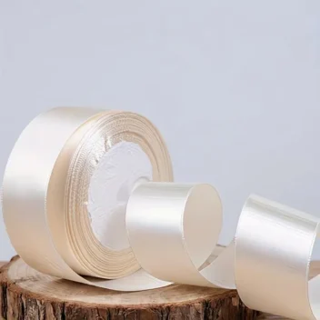 Kleurechte weergave van de 2,5 cm brede rol crème satijn lint op een houten ondergrond