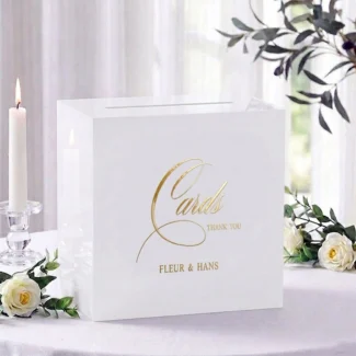 Valentina acryl enveloppendoos in wit met gouden Cards Thank You opdruk en namen Fleur en Hans, veilig afgesloten, op receptietafel met kaarsen en bloemen