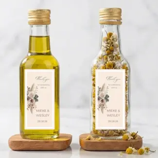 Twee kleine flesjes met Boho Blush etiket, één met olijfolie en de ander met gedroogde kamille, beide voorzien van een bedanklabel voor bedankjes bruiloft.